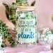 Decorative jar with 'it's not hoarding if it's plants' text, surrounded by small plants and disco balls on a pink background.