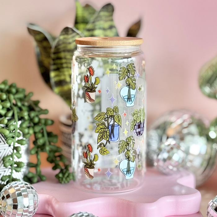 Decorative jar with plant designs on a pink stand against a pink wall with festive decorations.