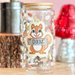 Decorative glass jar with a squirrel design on a wooden surface with a pink background.