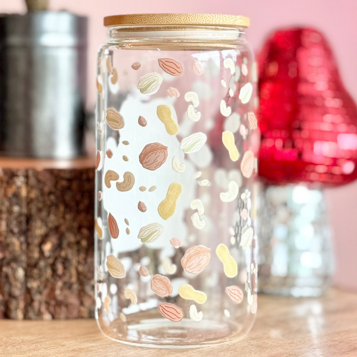 Decorative glass jar with colorful patterns on a wooden surface with a pink background.